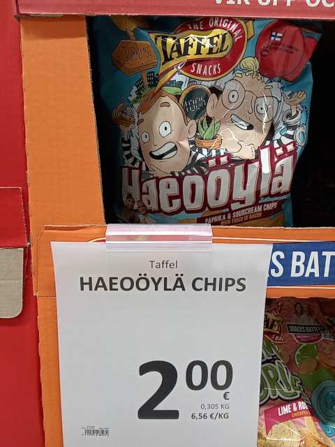 Isossa pahvilaatikossa 305 gramman sipsipusseja, edessä A4:lle tulostettu hintalappu: "Taffel Haeoöylä Chips, 2,00 € (6,56 €/kg)
