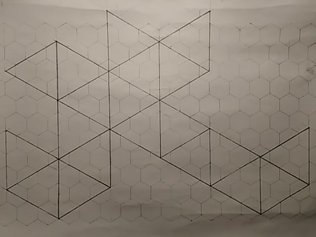 Paperiarkki, himmeällä harmaalla kuusikulmioista koostuva ruudukko, päälle piirretty tummemmalla lyijykynällä 20 ketjutettua kolmiota, ikosaedrin verkoksi aseteltuna.